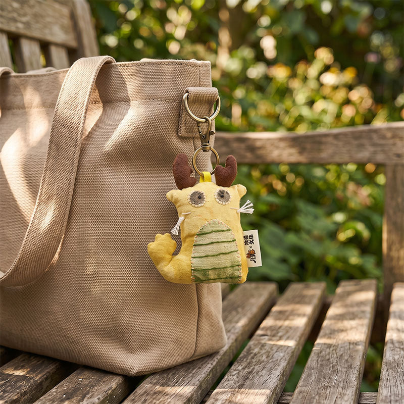 Handgefertigter Goldhorn-Drachen-Taschenanhänger aus Leinen – side view showing shape and hand-stitched details